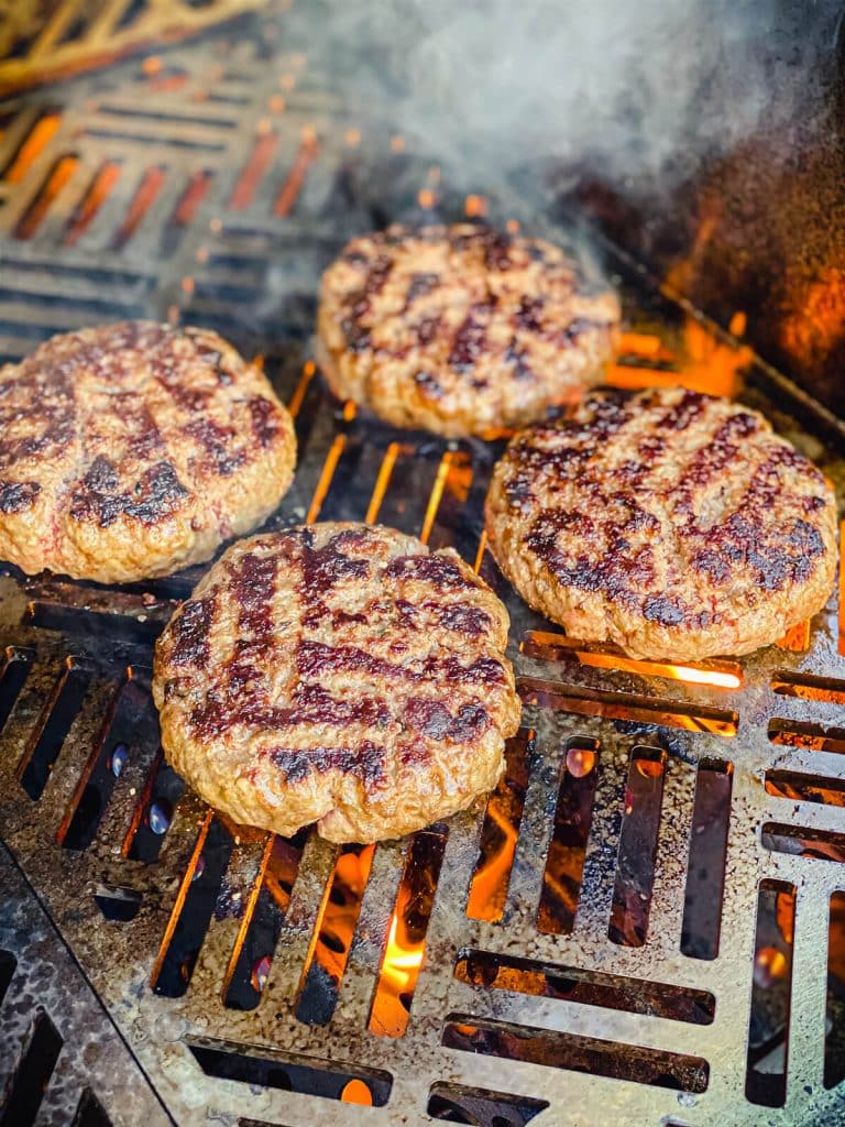 charred hamburgers on a grill over flames