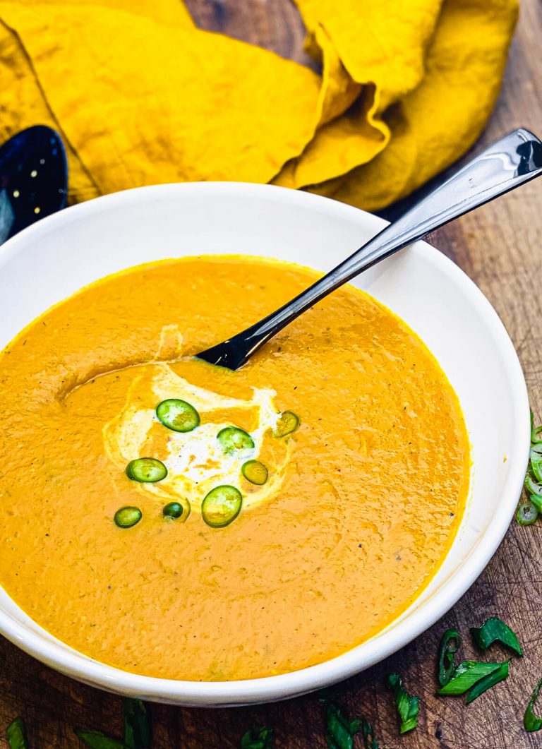 roasted vegetable soup in a bowl with a black spoon