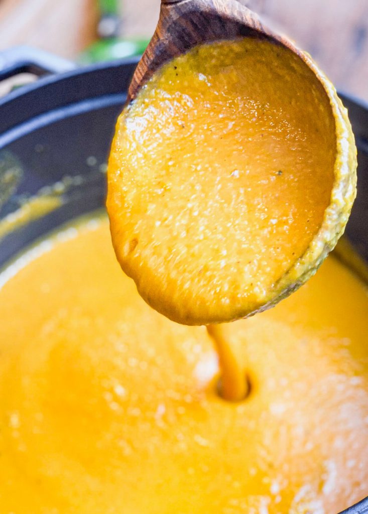 roasted vegetable soup pouring from a laddle