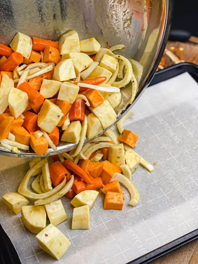 root vegetables being poured onto a baking sheet