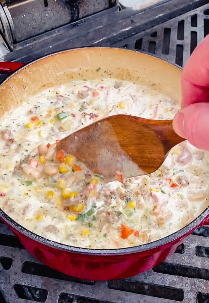 stirring a pot of smoked chicken chili