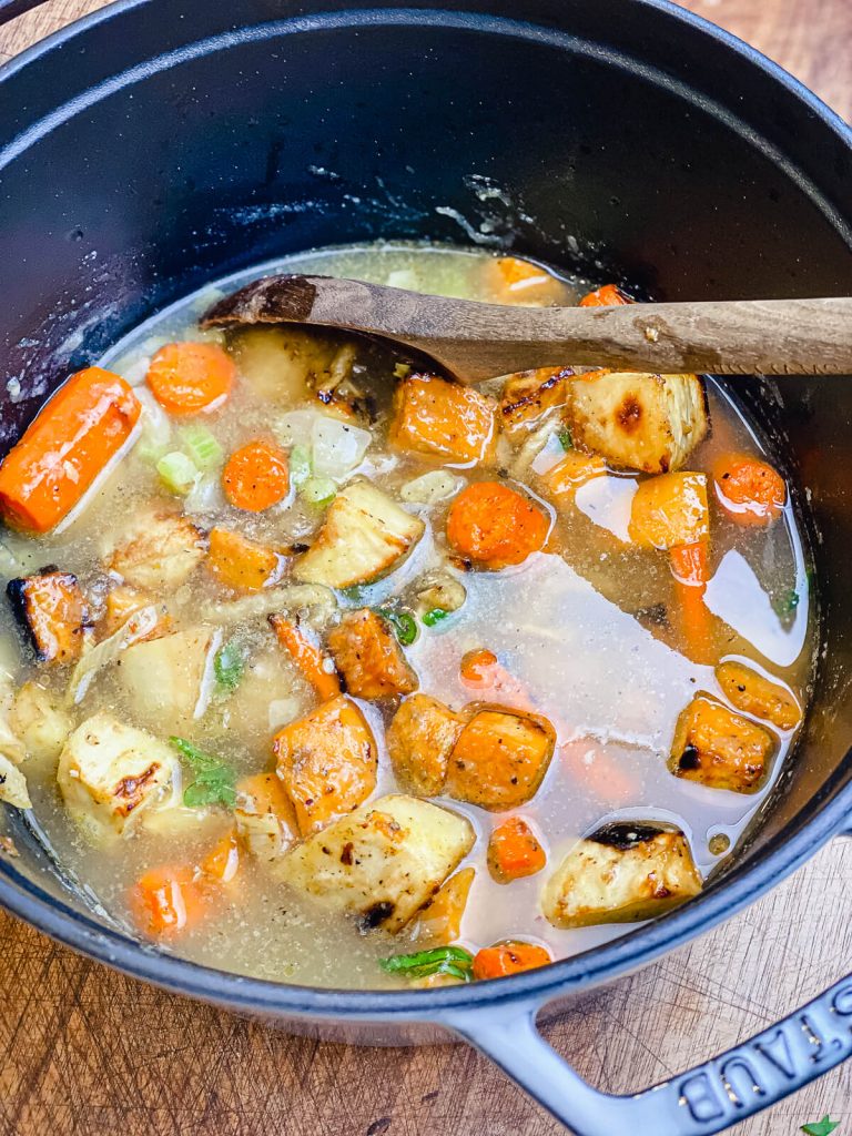 stock added to roasted vegetables in a dutch oven