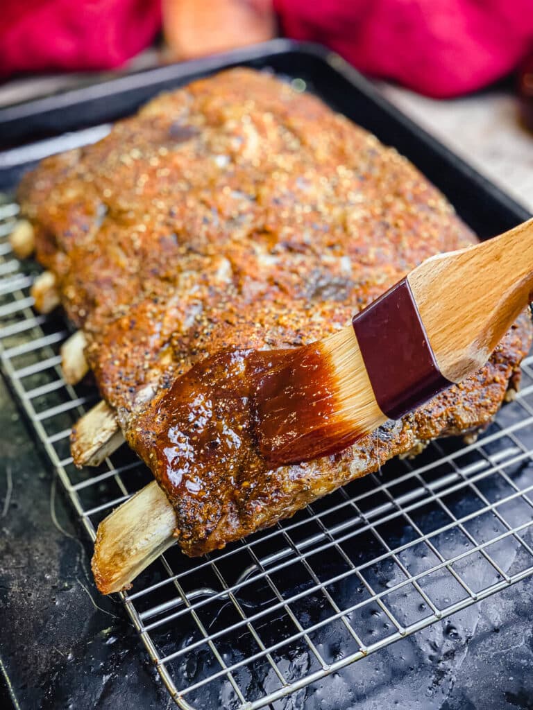 bbq sauce being applied to beef ribs