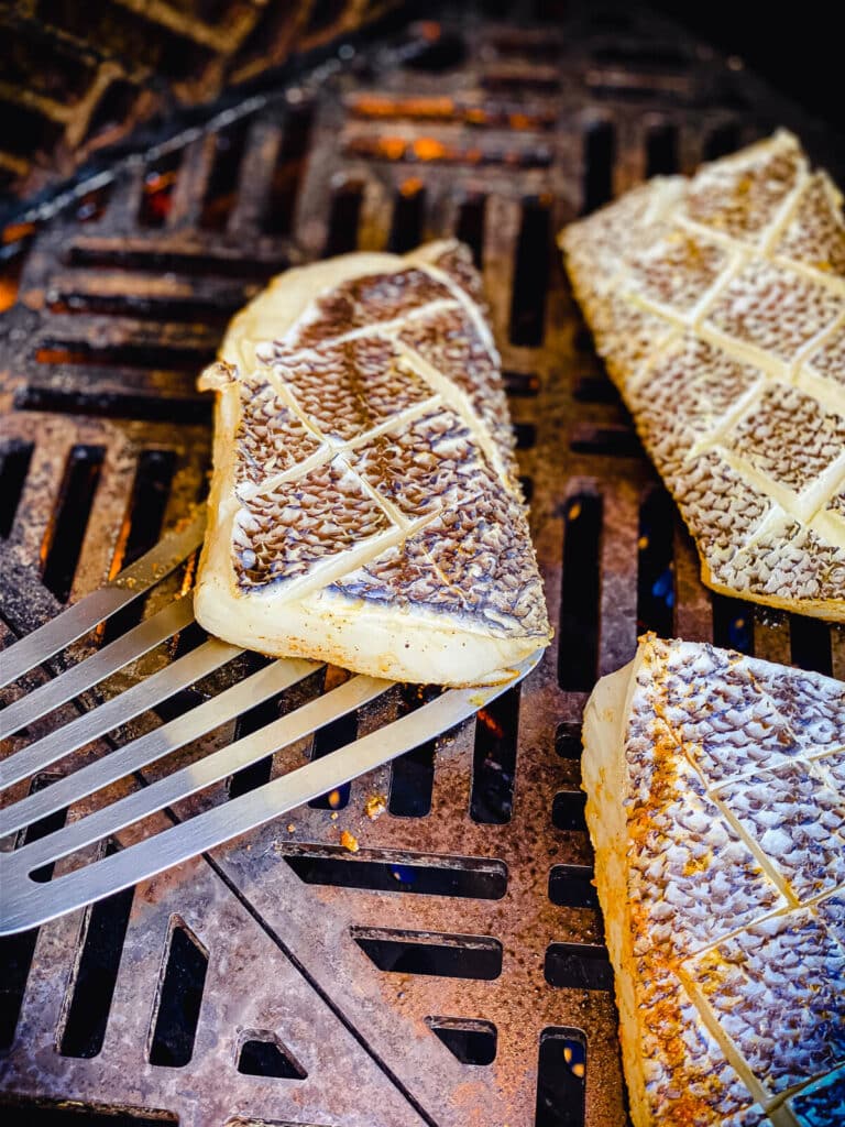 fish spatula sliding under a piece of grilled chilean sea bass