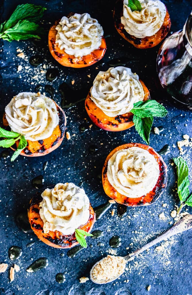 grilled peaches with ice cream and a spoon on a cutting board