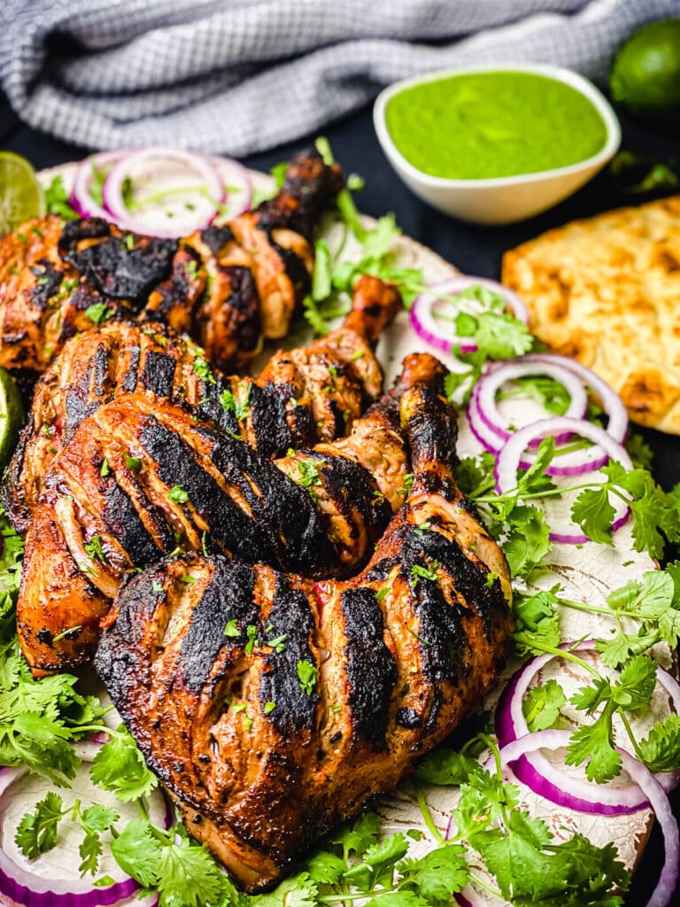 platter full of tandoori chicken with greens and onions