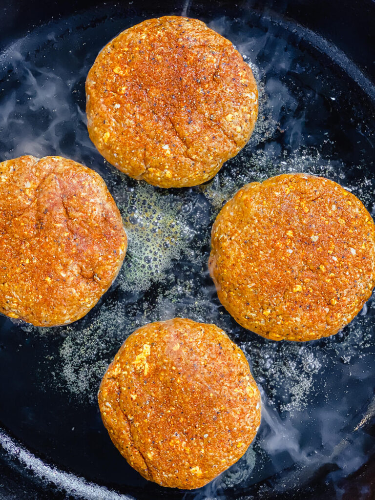 Nashville hot chicken burgers being fried in a pan