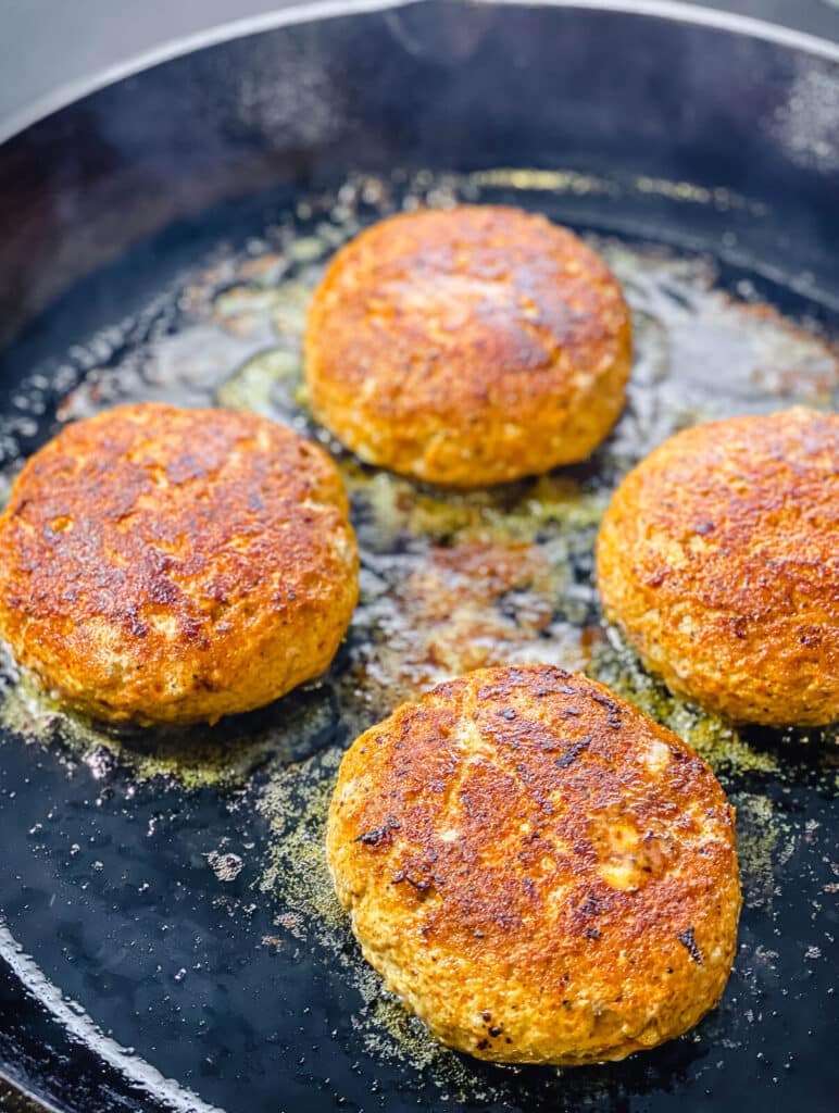searing Nashville hot chicken burgers in a cast iron pan