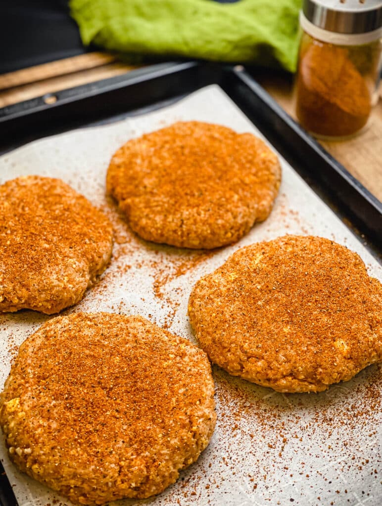 uncooked Nashville hot chicken burger patties on a tray