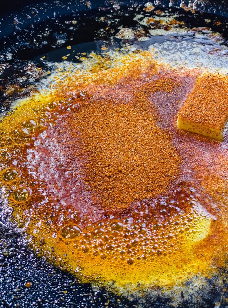 sauce for Nashville hot chicken burgers being made in a cast iron skillet