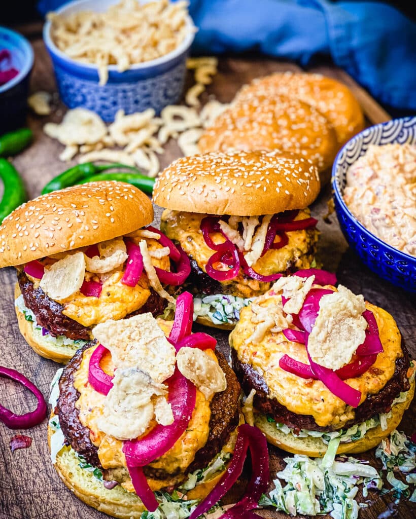 pimento cheeseburgers on a cutting board with a bowl of pimento cheese