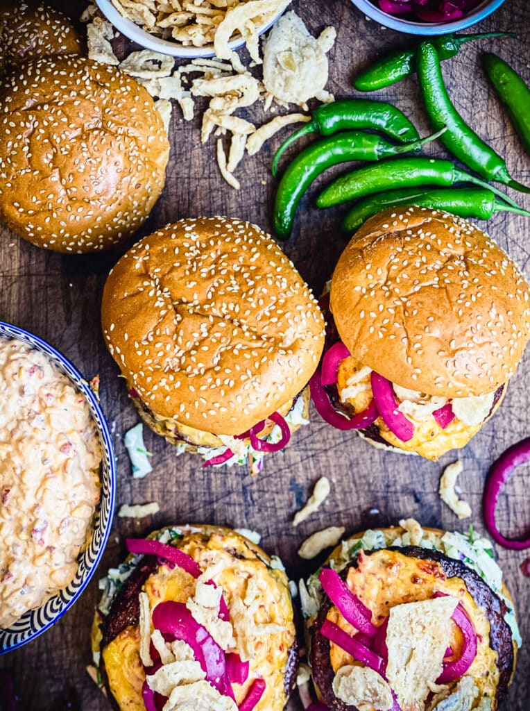 overhead shot of pimento cheeseburgers with peppers and a bowl of cheese