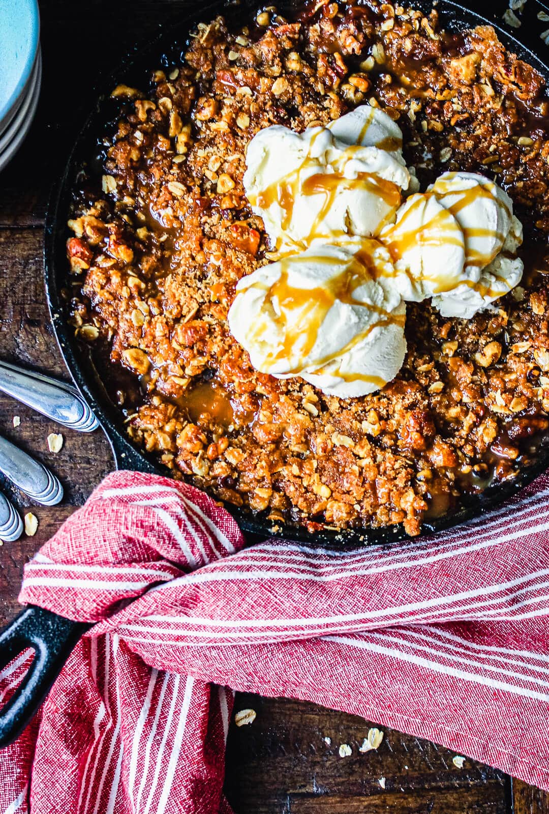 smoked apple crisp in a cast iron pan with red towel wrapped around the handle
