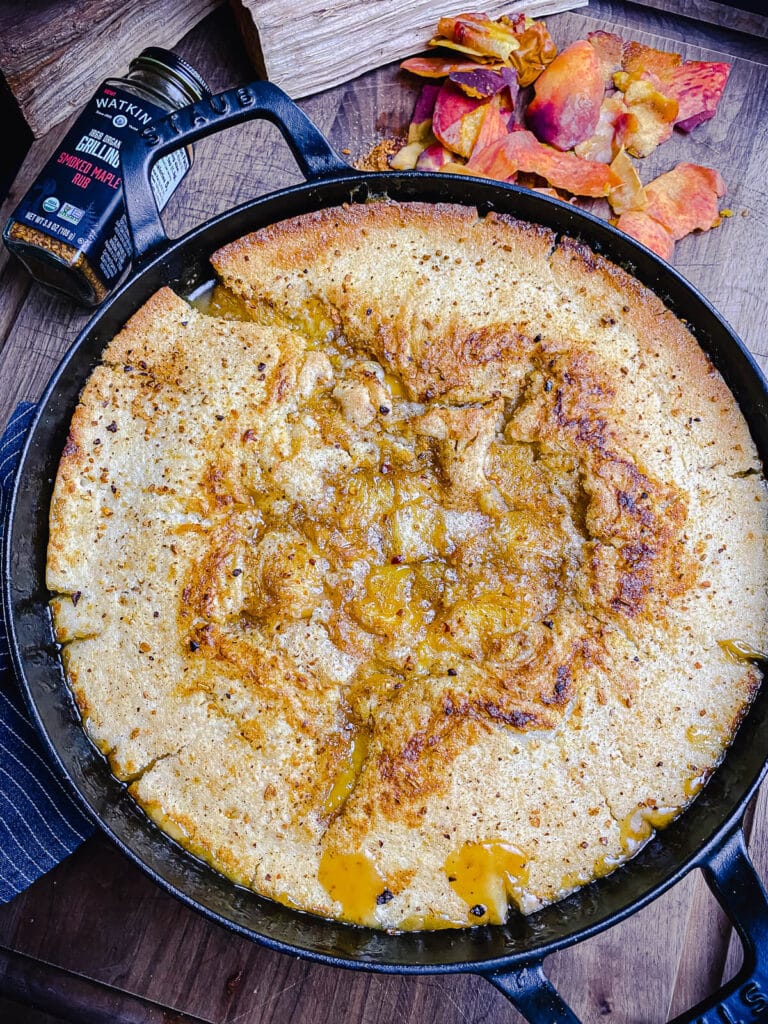 smoked peach cobbler in a cast iron pan with peach peelings
