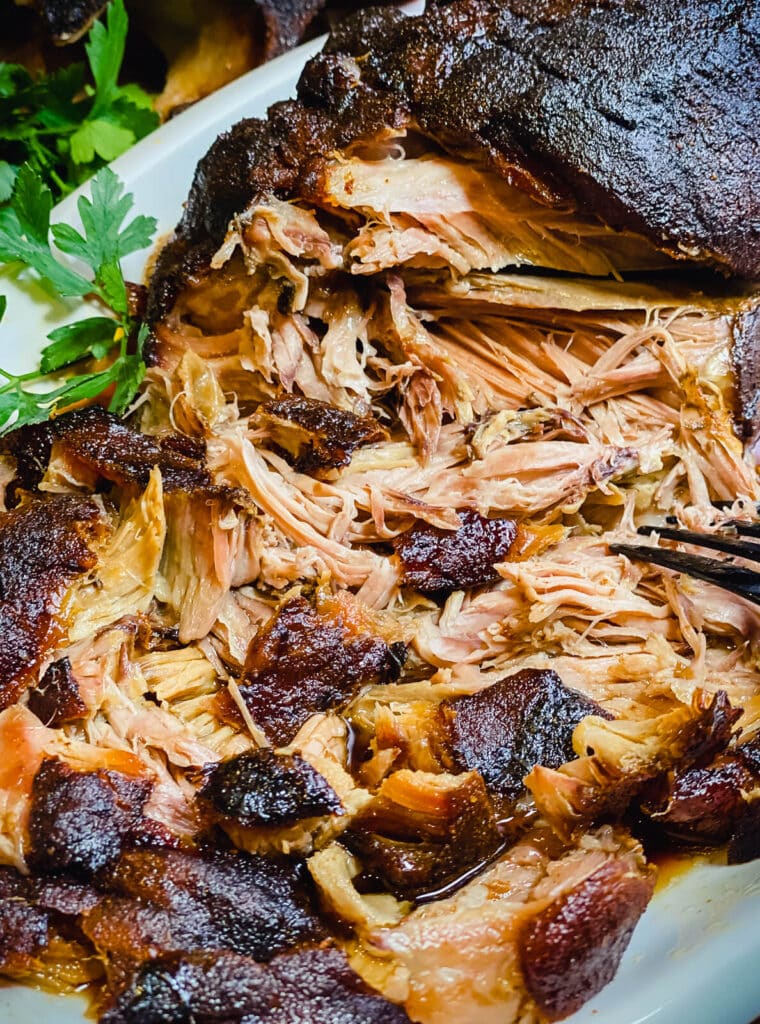 pork that's been pulled apart sitting on a plate with green parsley