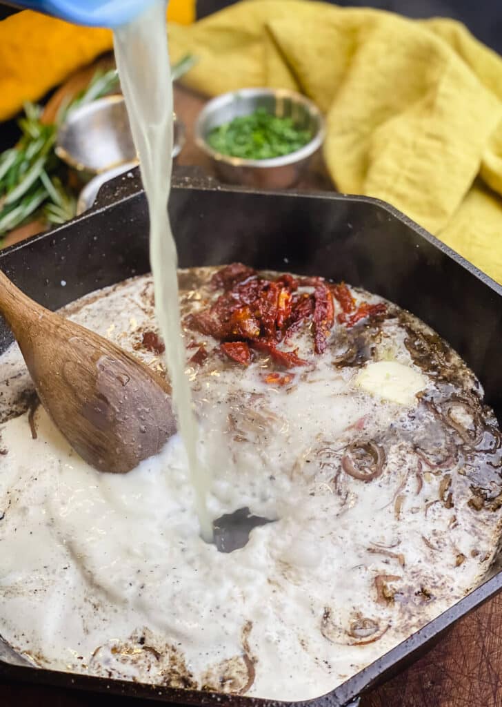 chicken stock being added to a pan for pan seared pork chops