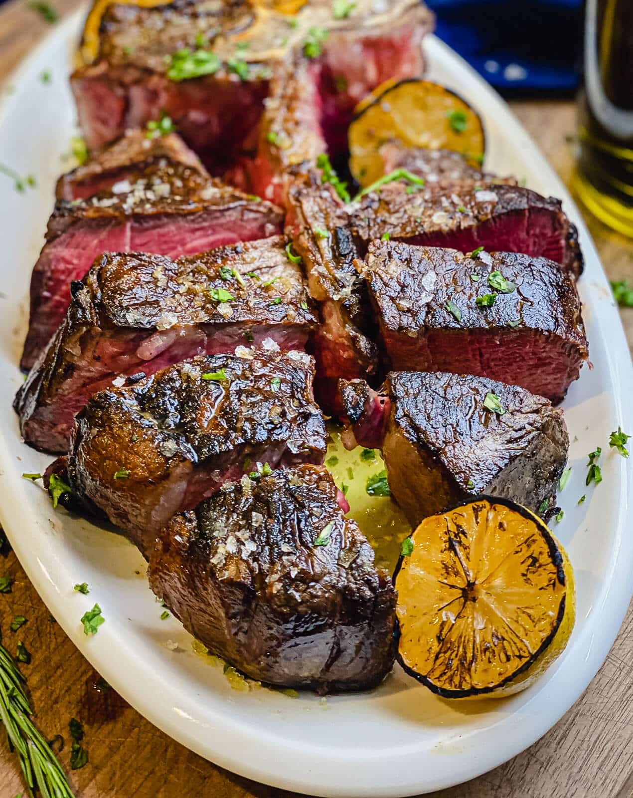 steak florentine sliced on a platter with grilled lemons