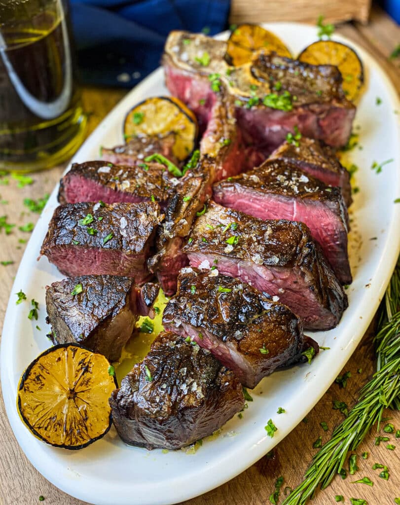 florentine steak sliced and on a white platter for  rosemary and olive oil