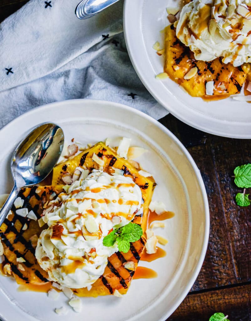 plate of grilled pineapples topped with ice cream and mint