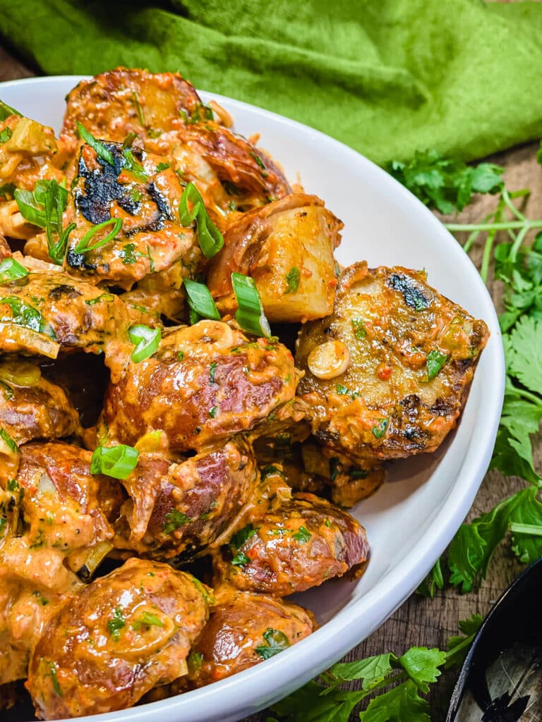 bowl of grilled potato salad garnished with green onions