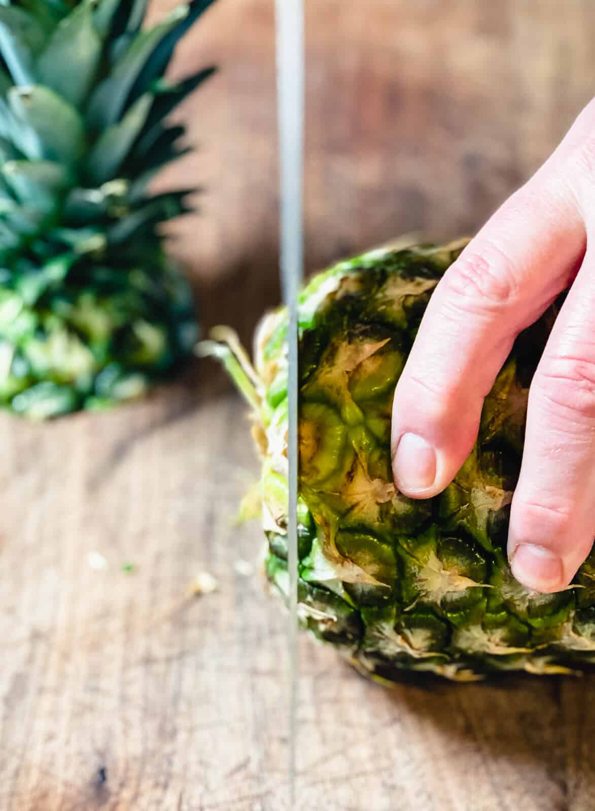 knife cutting off the bottom of a pineapple