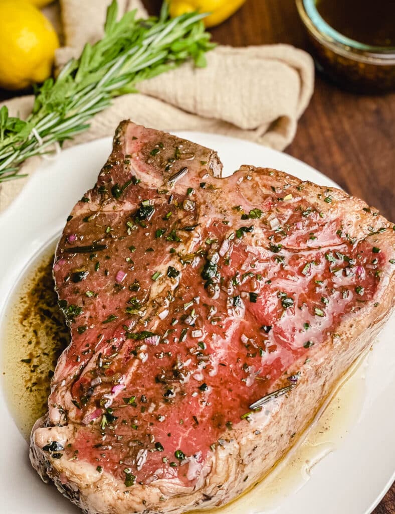 marinated porterhouse steak sitting on a white plate