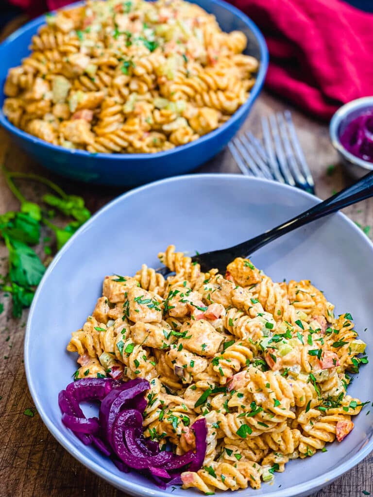 Nashville hot chicken salad pasta in a bowl with pickled red onions and a fork