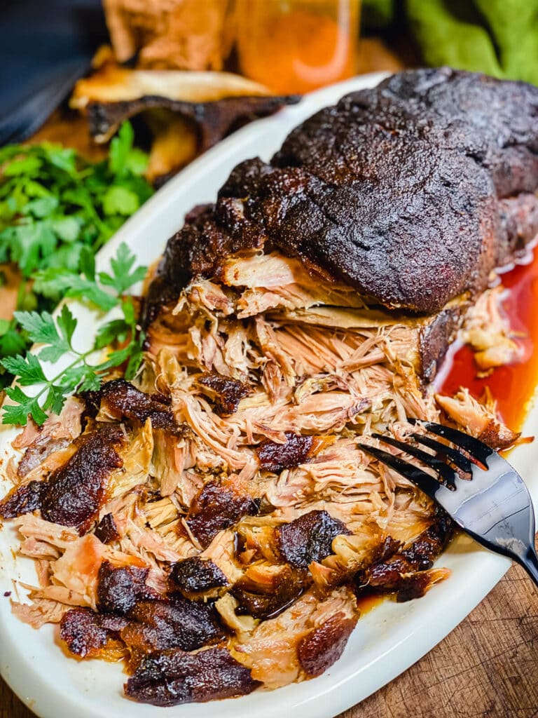 pork butt that has been partially pulled apart sitting on a platter