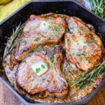 pan seared pork chops in a cast iron pan, with rosemary and butter