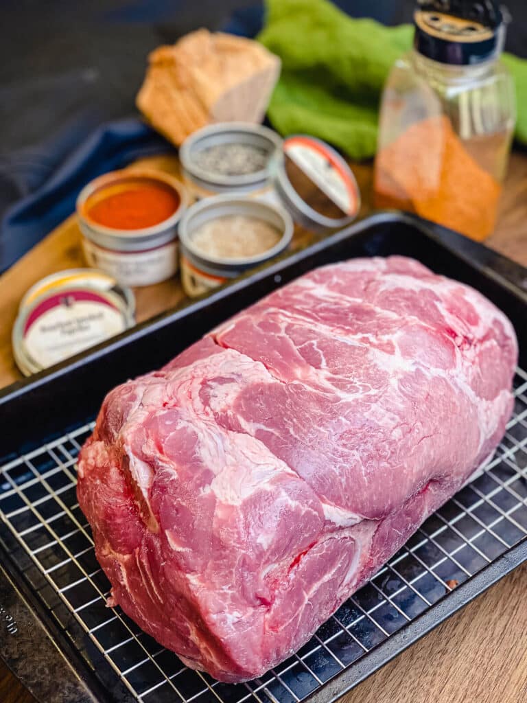 uncooked Boston butt sitting on a wire cooling rack