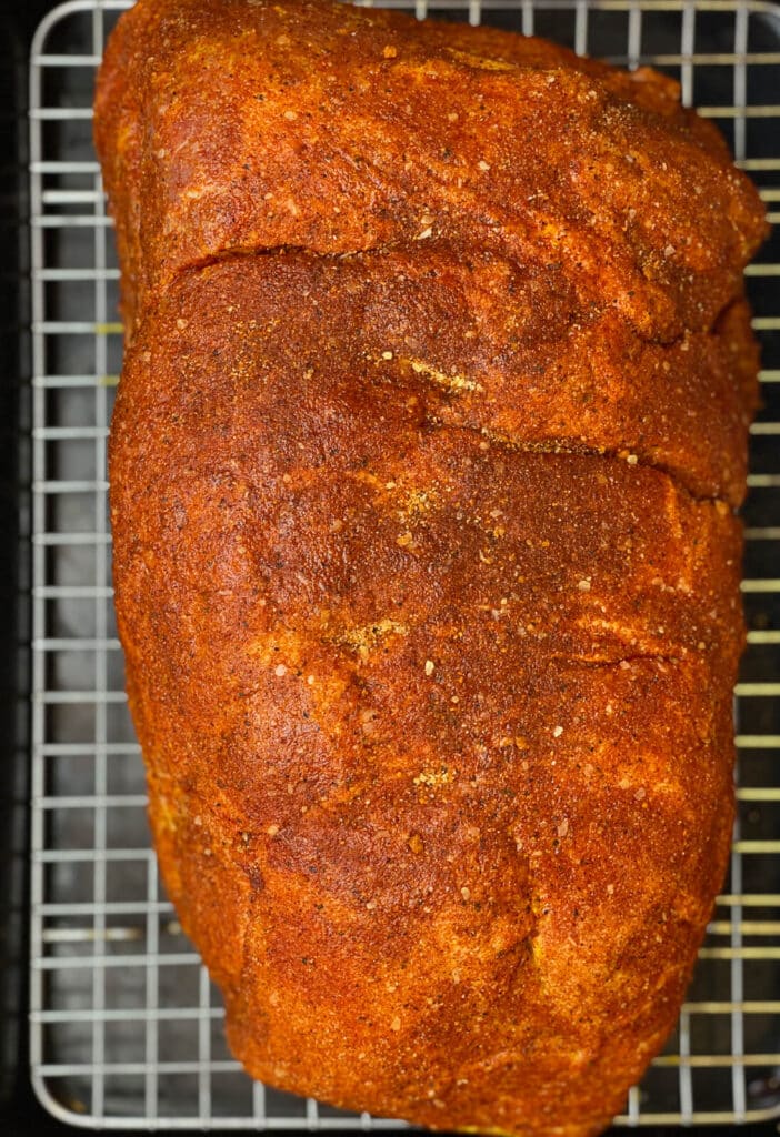 uncooked pork shoulder seasoned with homemade BBQ rub