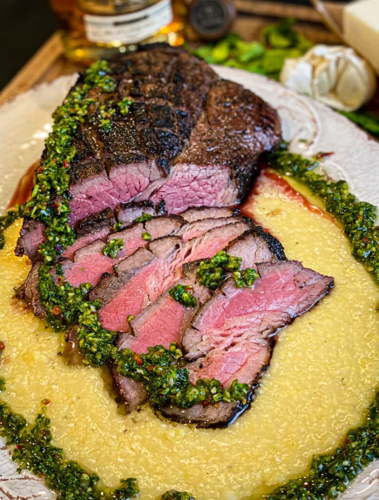 sliced London broil with chimichurri on a platter
