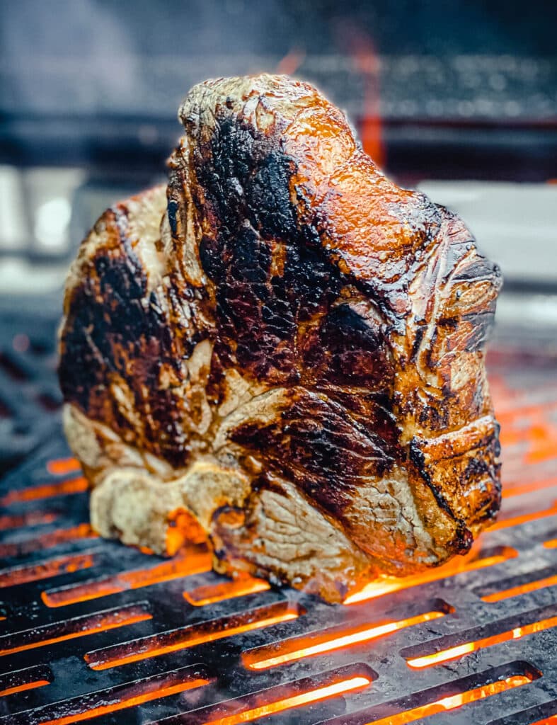 steak florentine grilling on its edge over flames