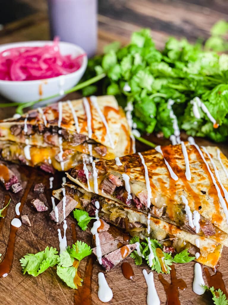 two stacks of steak quesadillas with sour cream