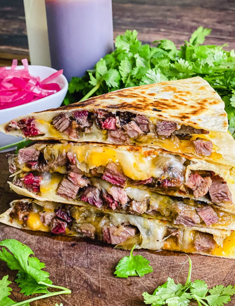meat spilling out of a steak quesadilla sitting on a cutting board