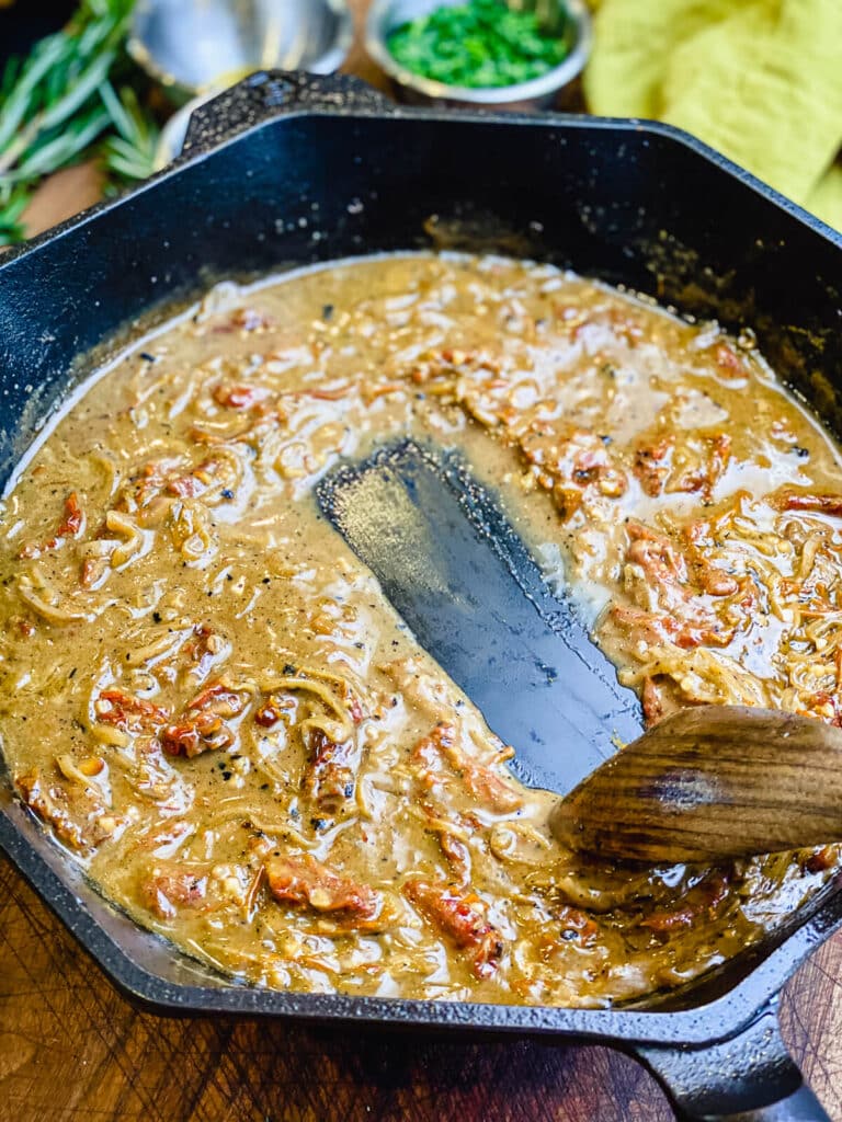 sun-dried tomato sauce in a cast iron pan with a wooden spoon