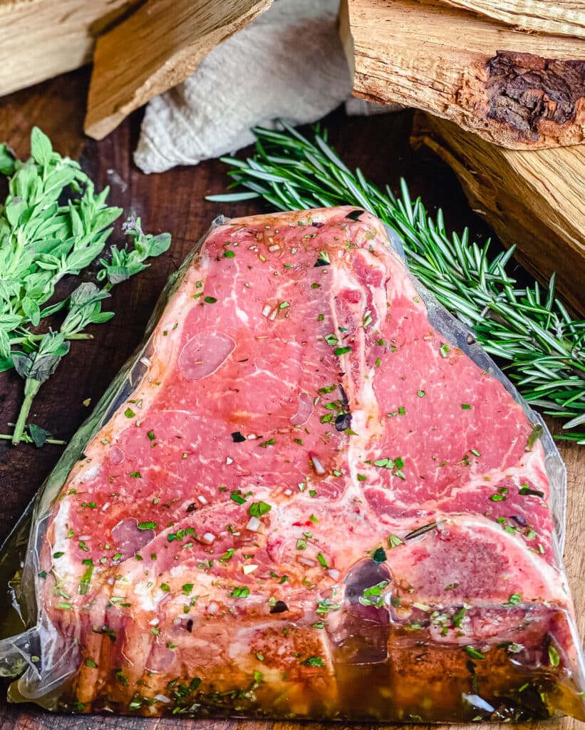 porterhouse steak marinating in a plastic bag with herbs