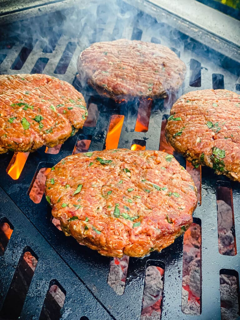 raw Mexican burger patties placed on a hot grill surface