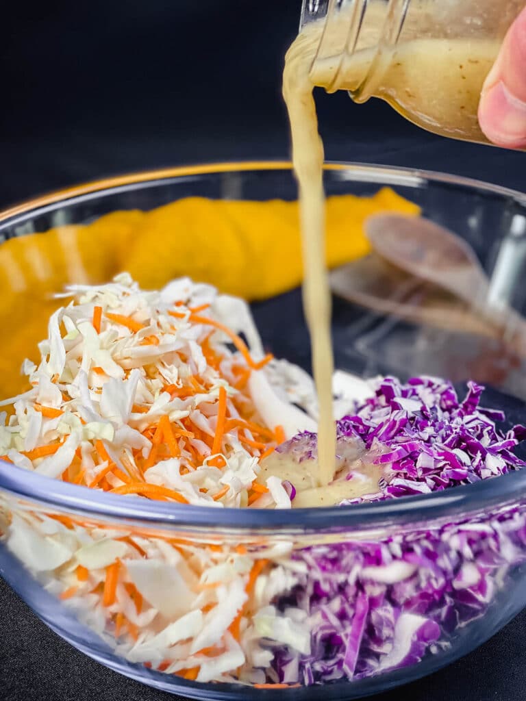 no mayo coleslaw dressing being poured into a bowl of cabbage and carrots