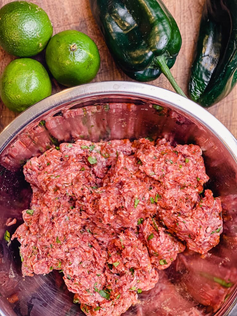 ground beef mixed with seasoning in a mixing bowl