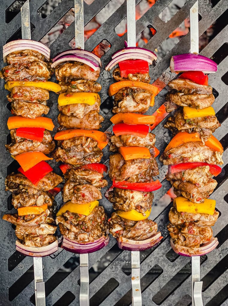 overhead shot of chicken skewers on a grill grate over fire