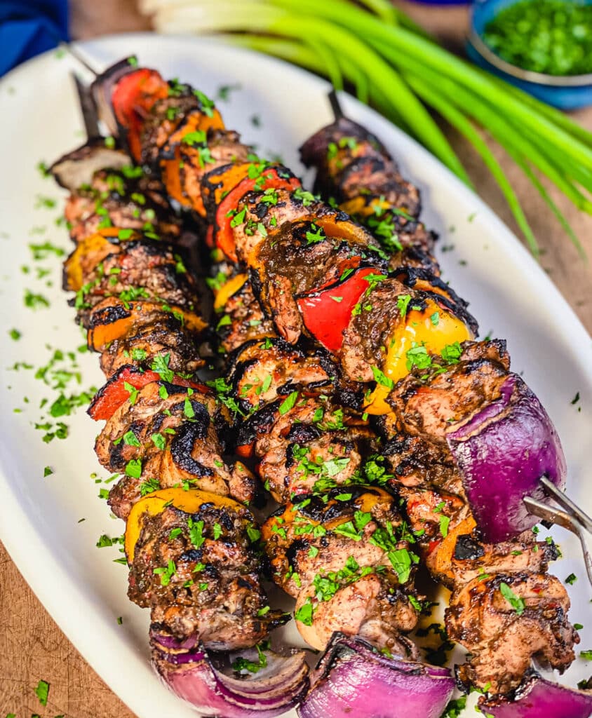 white platter with Jamaican jerk chicken skewers and green onions