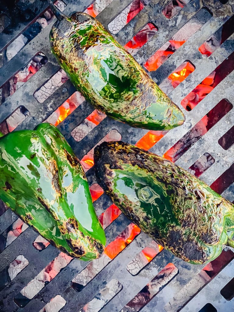 poblano peppers roasting over hot coals on a grill