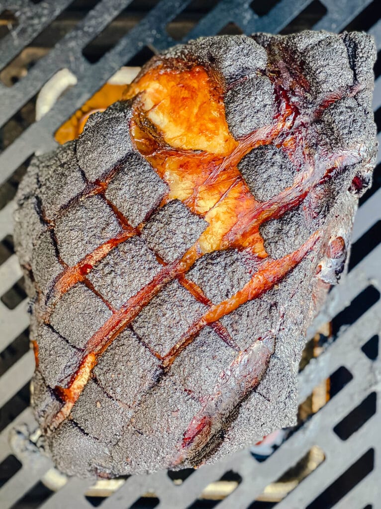 apple juice brined pork shoulder on a smoker with dark crust formed on outside