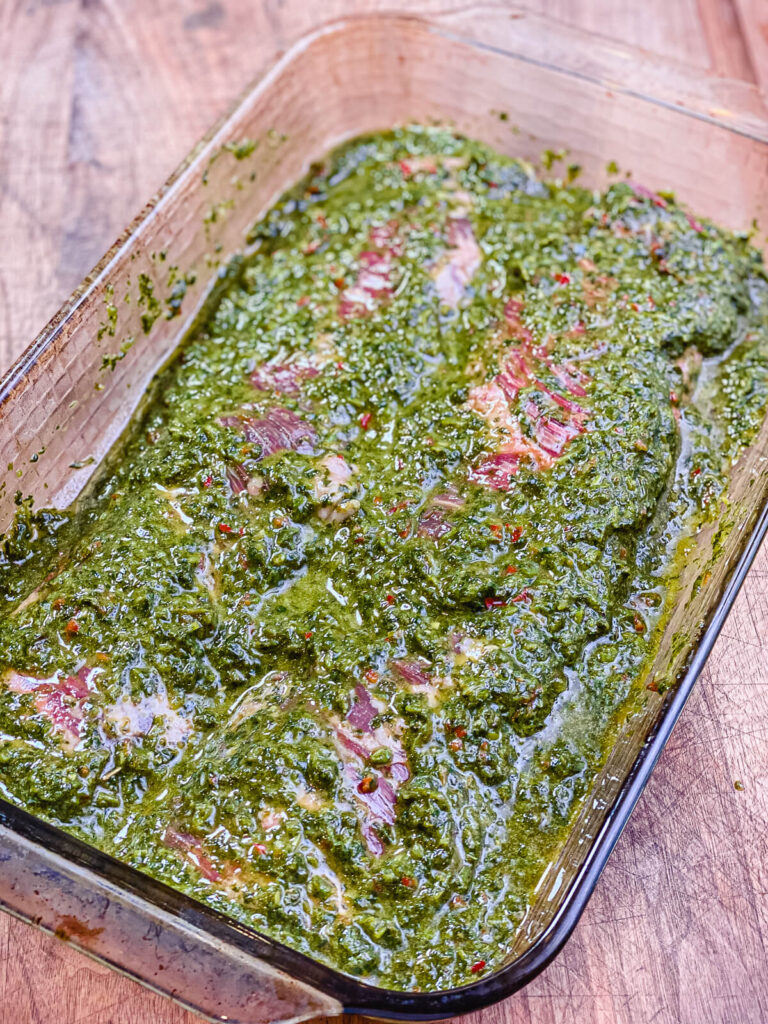 skirt steak in a dish covered with chimichurri