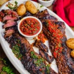 churrasco steak on a platter with chimichurri sauce and potatoes