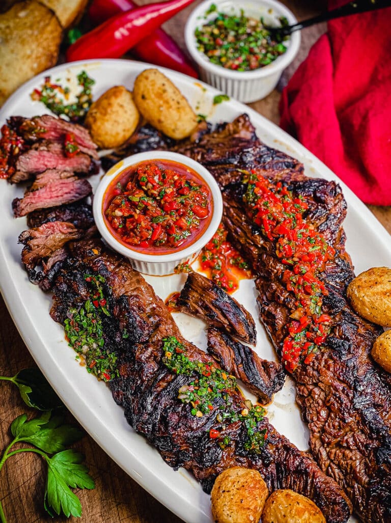 churrasco steak on a platter with chimichurri sauce and potatoes