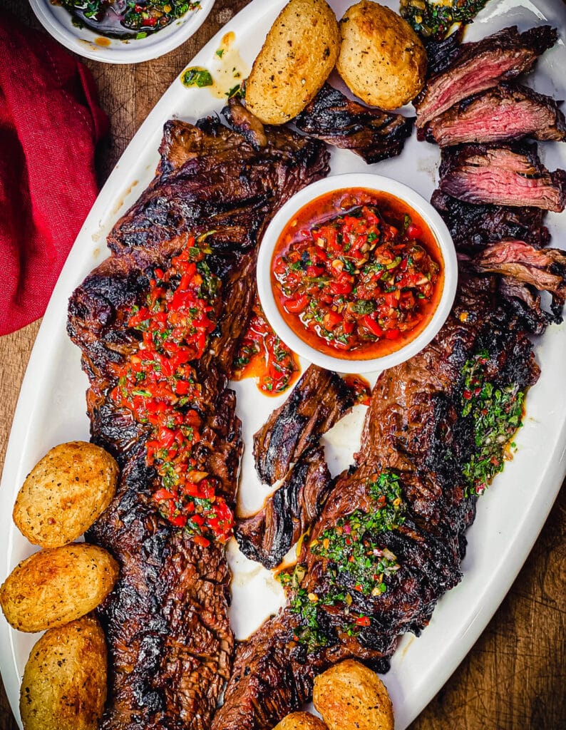 churrasco steak on a platter with with potatoes as viewed from overhead