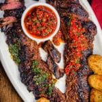 churrasco steak on a white platter with chimichurri