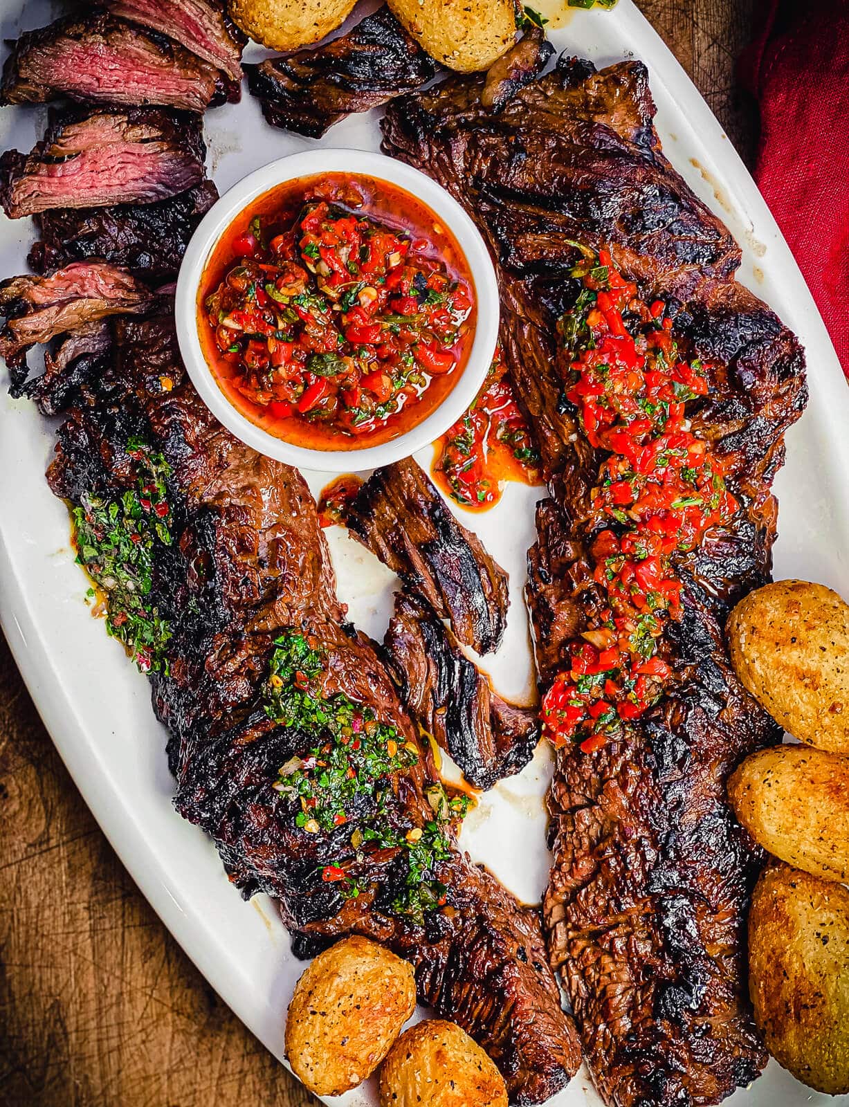 churrasco steak on a white platter with chimichurri